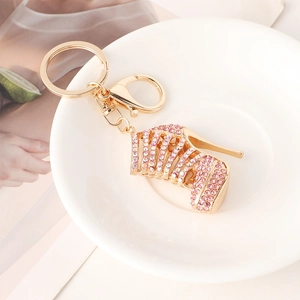 Golden high heel keychain with pink rhinestones on a white plate with magazine