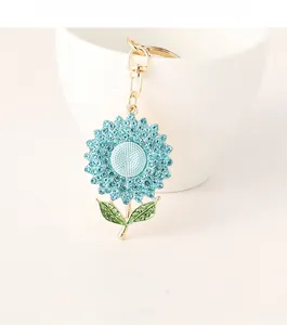 Close-up of light blue rhinestone sunflower keychain hanging on a white ceramic cup