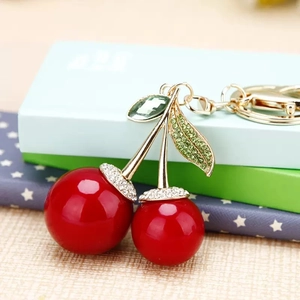 Porte-clés cerise avec boules rouges et fermoir doré sur une boîte cadeau élégante