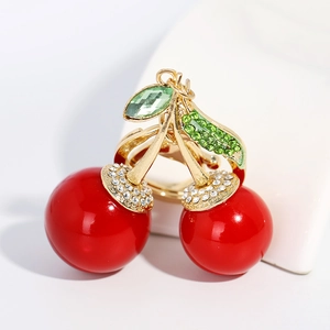 Porte-clés cerise chic avec feuilles dorées et cristaux verts sur support blanc