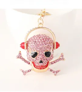 Close-up of pink crystal-encrusted skull keychain with red headphones and golden clip