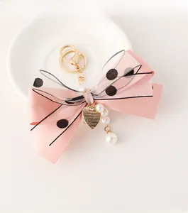 Close-up of pink ribbon bow keychain with polka dot mesh and faux pearl charms
