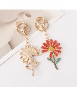 Detailed comparison of golden hollow daisy keychain and colorful rhinestone floral bag charm