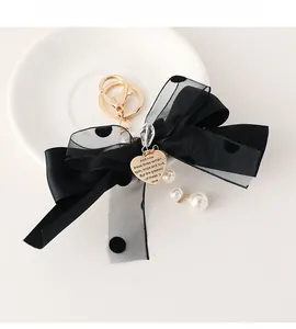 Detail of black polka dot mesh bow keychain with gold heart charm and white faux pearls