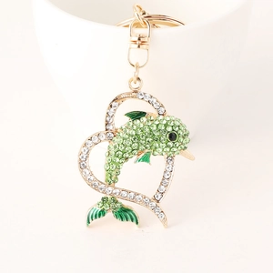 Creative gold dolphin heart keychain with green rhinestones on a white ceramic cup