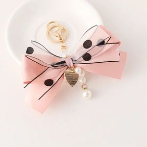 Pink ribbon keychain with mesh bow and engraved heart charm on white surface