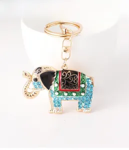 Close-up of golden elephant keychain featuring blue rhinestones and green enamel patterns