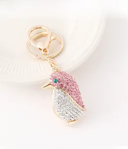Detalle de llavero de pingüino con cristales rosas y blancos sobre metal dorado