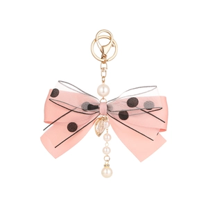 Pink ribbon bow keychain with pearls and gold heart charm on a white background