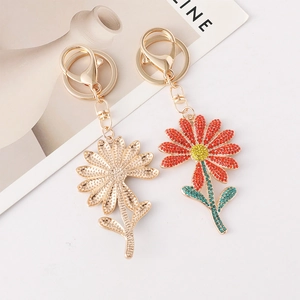 Elegant gold daisy keychain and rhinestone sunflower pendant on minimalist background
