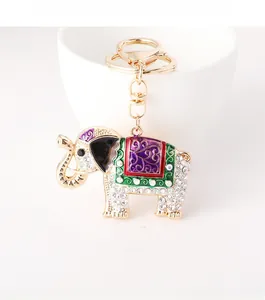 Detail of elephant keychain with sparkling rhinestones and colorful enamel on white ceramic cup