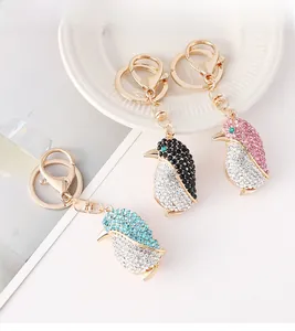 Detalle de llaveros de pingüino con diamantes de imitación en azul, negro y rosa oro