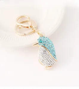 Detalle del llavero de pingüino dorado con brillantes strass azules en un plato blanco