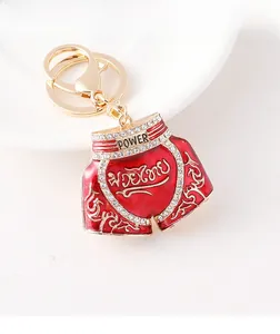 Detail of red Muay Thai shorts keychain with gold trim, rhinestones and Power engraving
