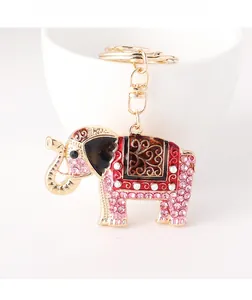 Close-up of golden elephant keychain with pink crystals and enamel on a white bowl