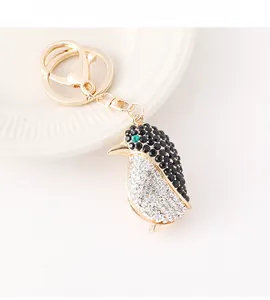 Detalle de llavero de pingüino con cristales blancos y negros en base de metal oro