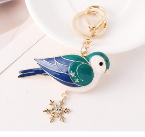 Detailansicht eines kreativen Vogel-Schlüsselanhängers mit Emaille und Gold-Schneeflocke