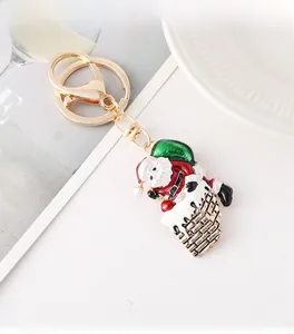 Detailed view of enamel Santa chimney keychain with gold lobster clasp on white tray