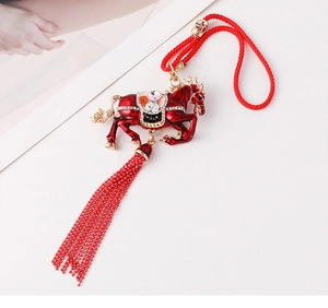 Detailed close-up of a red metal horse pendant with enamel finish and beaded tassels