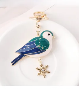 Makrofoto von Vogel-Schlüsselanhänger mit Emaille und Gold-Schneeflocke-Anhänger