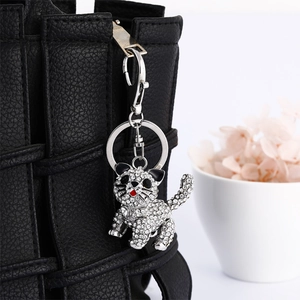 Sparkling rhinestone 3D cat keychain hanging on a black leather bag for women