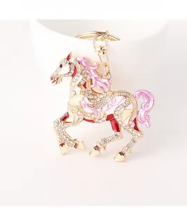 Close-up of pink enamel horse keychain with sparkling rhinestones on a white cup