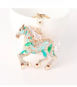 Close-up of golden horse keychain with green enamel detail and sparkling rhinestones