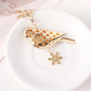 Goldener Vogel Schlüsselanhänger mit hohlem Herzdesign und Schneeflocke auf Keramikteller
