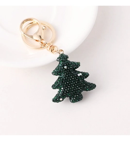 Macro view of green rhinestone Christmas tree keychain with polished golden lobster clasp