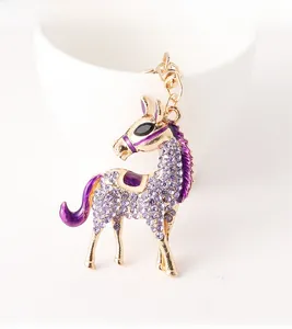 Detailed close-up of a golden horse keychain with gradient purple rhinestones and enamel