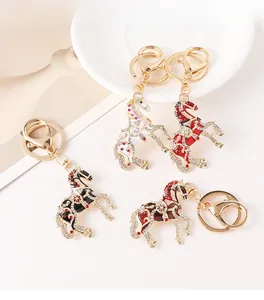 Détail de quatre porte-clés cheval ornés de strass en plusieurs couleurs sur une assiette en céramique