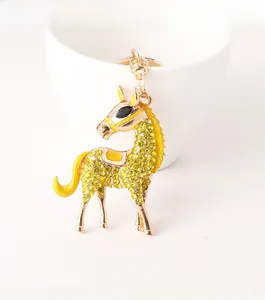Detail of a gold-toned flying horse keychain with yellow rhinestones and enamel accents