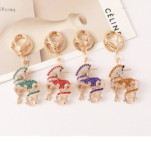 Détail de quatre porte-clés licorne en cristal avec strass verts, rouges, bleus et ambrés