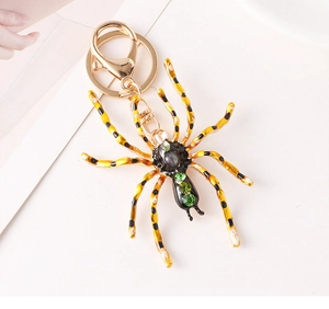 Détail d'un porte-clés araignée dorée avec pattes émaillées jaunes et strass brillants