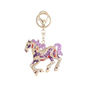 Golden horse keychain with purple enamel and sparkling crystals on white background