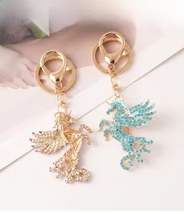 Vue détaillée de porte-clés licorne en métal doré et bleu avec strass étincelants et ailes