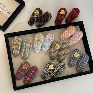 Détail de barrettes à cheveux en tweed coloré avec boucles dorées en forme de cœur