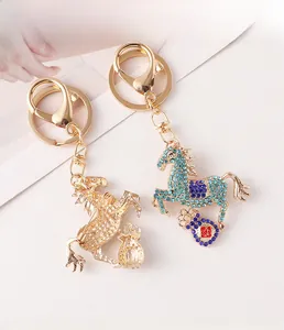 Close-up of golden horse and money bag keychain with sparkling blue rhinestones