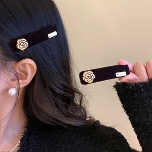 Elegant black velvet hair clip with a golden camellia flower accent for women