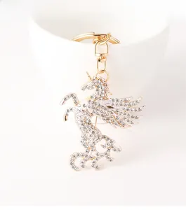 Détail d'un porte-clés licorne dorée orné de strass brillants sur un bol en céramique