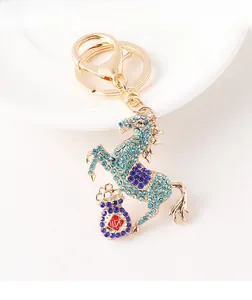 Close-up of golden horse keychain with blue rhinestones and a small money bag charm