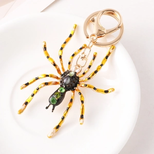 Porte-clés araignée aux motifs jaune et noir avec strass verts sur une assiette blanche