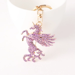 Porte-clés licorne doré orné de strass violets suspendu sur une tasse en céramique blanche