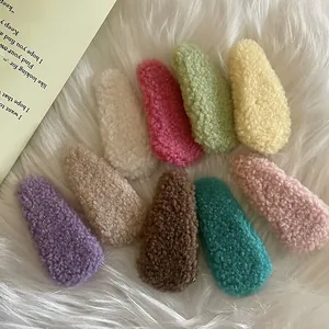Detailed top view of nine colorful plush cream puff hair clips on a soft faux fur background