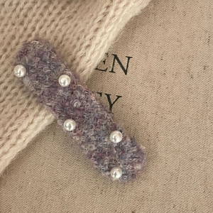 Detailed macro view of a vintage knit hair clip with pearls and purple tweed fabric