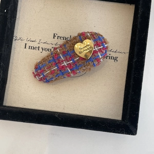 Détail macro d'une barrette en tweed de style français avec plaque en métal doré gravée