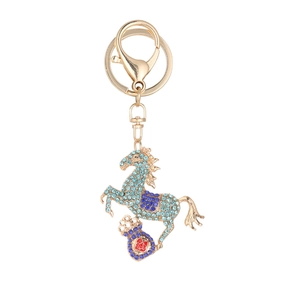 Golden horse keychain with blue crystals and lucky shield charm on white background
