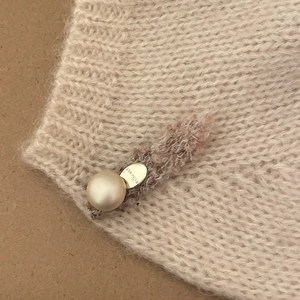Detailed close-up of knit butterfly hair clip with pearl and golden Princess metal plate