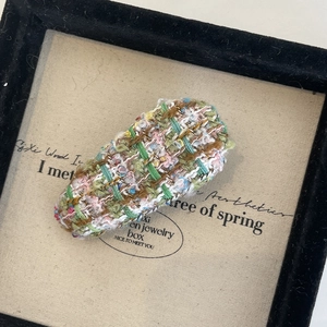 Vue détaillée de la texture du tissu en tweed multicolore sur une barrette de style français