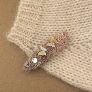 Detail of pink knitted hair clip with iridescent butterflies and shiny rhinestone